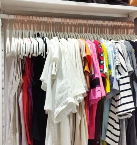 Bolsos y prendas ordenados en la balda superior de un vestidor