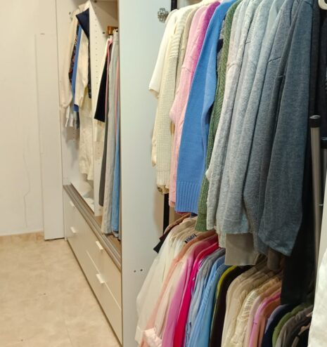 Habitación convertida en vestidor con ropa organizada