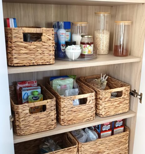 Cocina ordenada con cestas de fibra y productos agrupados por uso