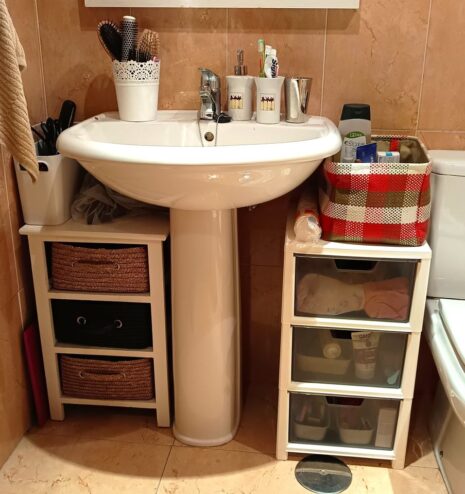 Baño organizado con cestas bajo el lavabo en un servicio de organización del hogar