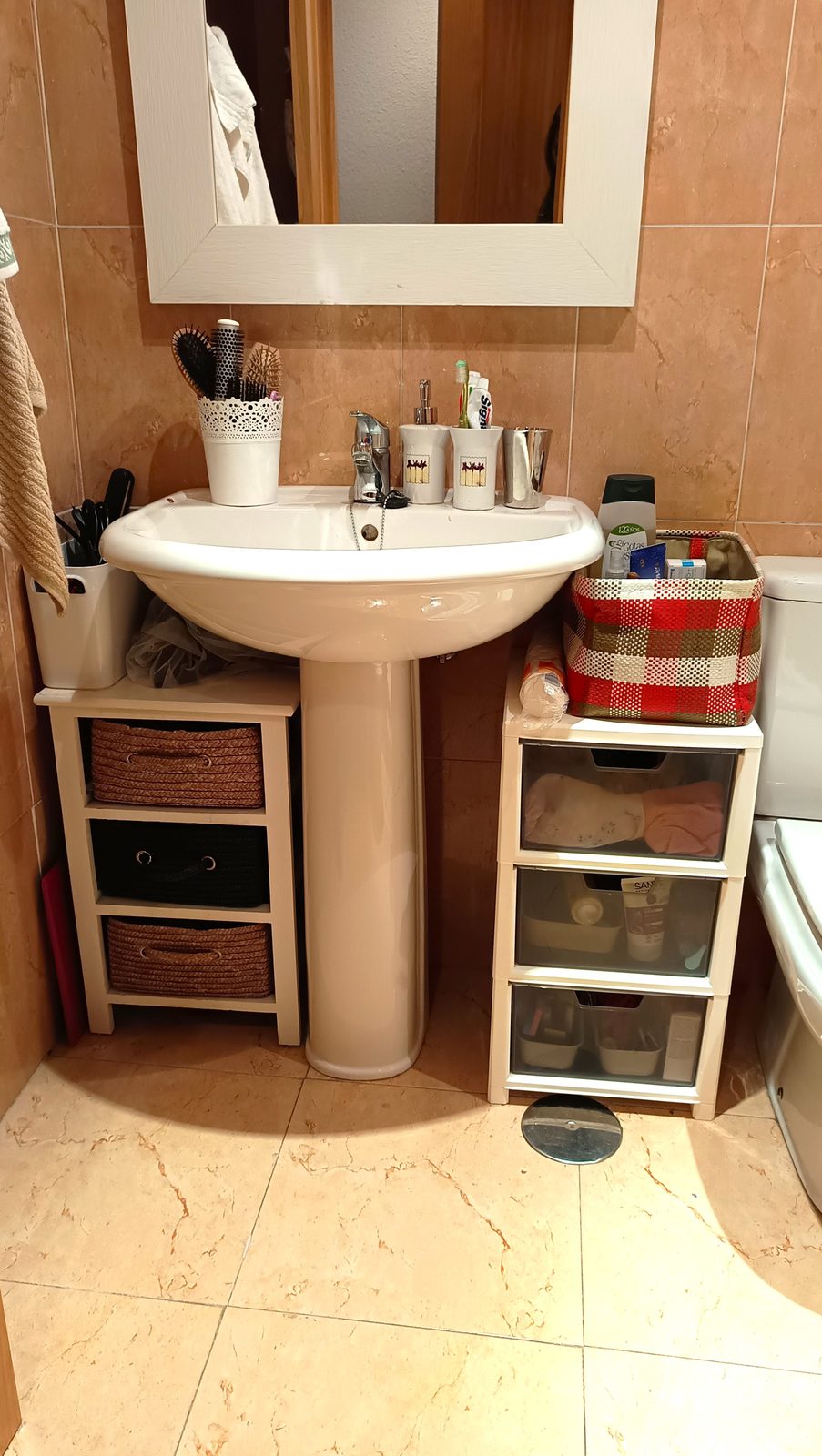 Baño organizado con cestas bajo el lavabo en un servicio de organización del hogar